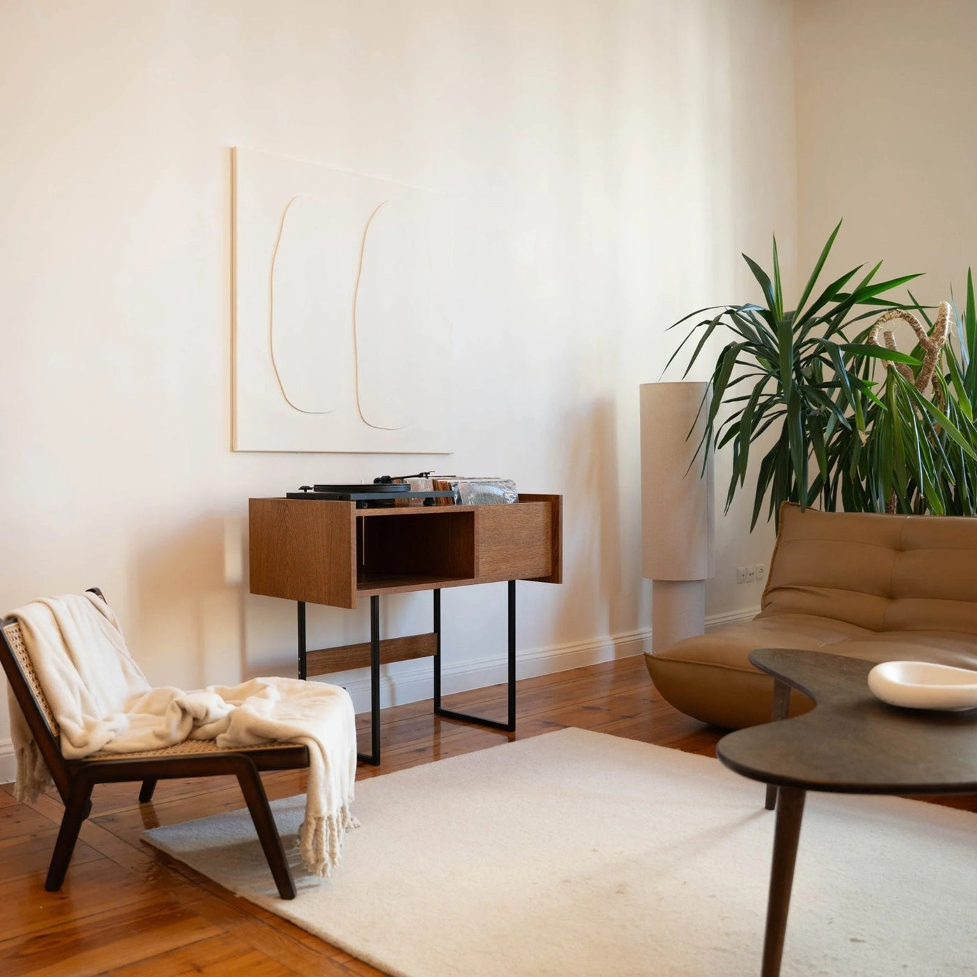 Platenkast van massief hout met platenspeler en LP-opslag in een sfeervolle moderne woonkamer